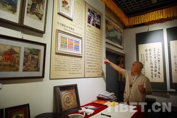 叶星生向中国西藏网记者介绍自己50年艺术展的部分作品，图中上方即为他第一幅作品《情系山茶花》。