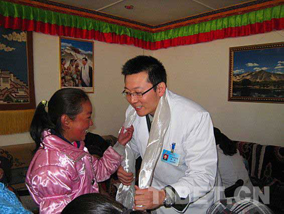 Photo shows that a Tibetan girl presents Khada to a doctor for saving her life out of congenital heart disease.[Photo/ China Tibet Online]