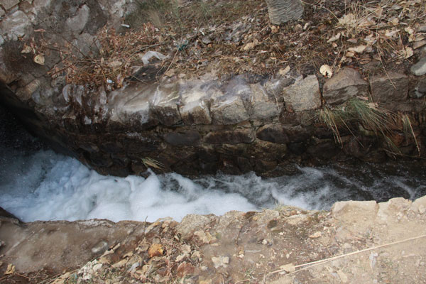 Photo shows that the fall of water providing motive power for the millstone in Gyami Watermill. [Photo/ China Tibet Online]