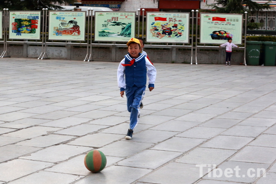 Photo shows a child playing football in a quiet alley. [Photo/ China Tibet Online]