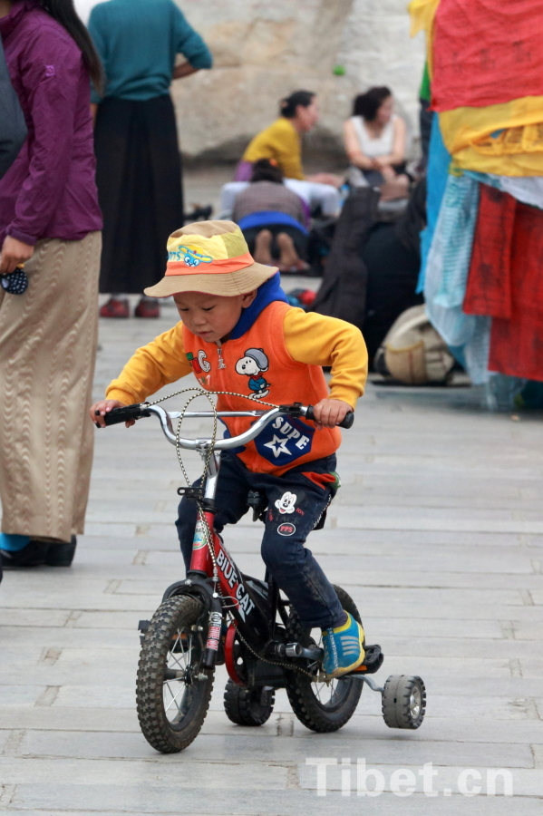 Photo shows a child riding in Lhasa. [Photo/ China Tibet Online]