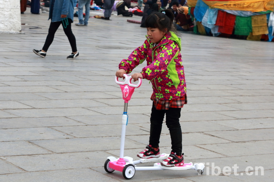 Photo shows a girl playing scooter in Lhasa. [Photo/ China Tibet Online]