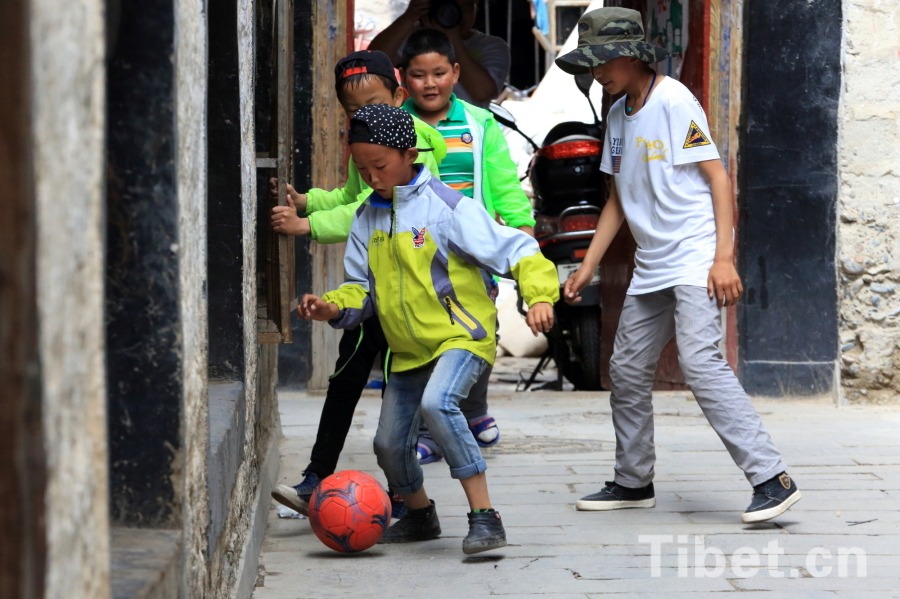 Photo taken on Jun.21, 2015 shows several Tibetan children playing a football game in an alley of the Barkor Street, Lhasa, capital of southwest China’s Tibet Autonomous Region. [Photo/China Tibet Online]