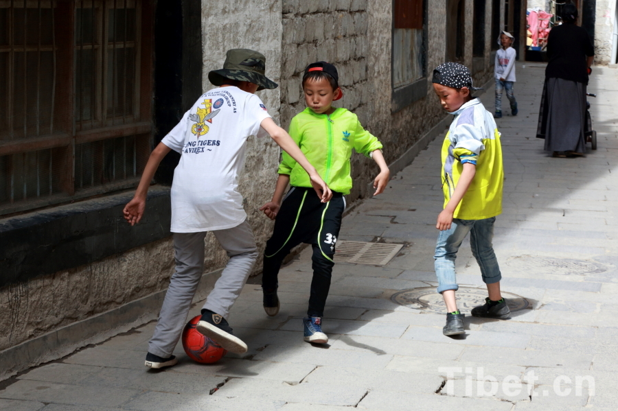 Photo taken on Jun.21, 2015 shows several Tibetan children playing a football game in an alley of the Barkor Street, Lhasa, capital of southwest China’s Tibet Autonomous Region. [Photo/China Tibet Online]