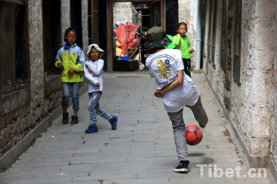 Photo taken on Jun.21, 2015 shows several Tibetan children playing a football game in an alley of the Barkor Street, Lhasa, capital of southwest China’s Tibet Autonomous Region. [Photo/China Tibet Online]