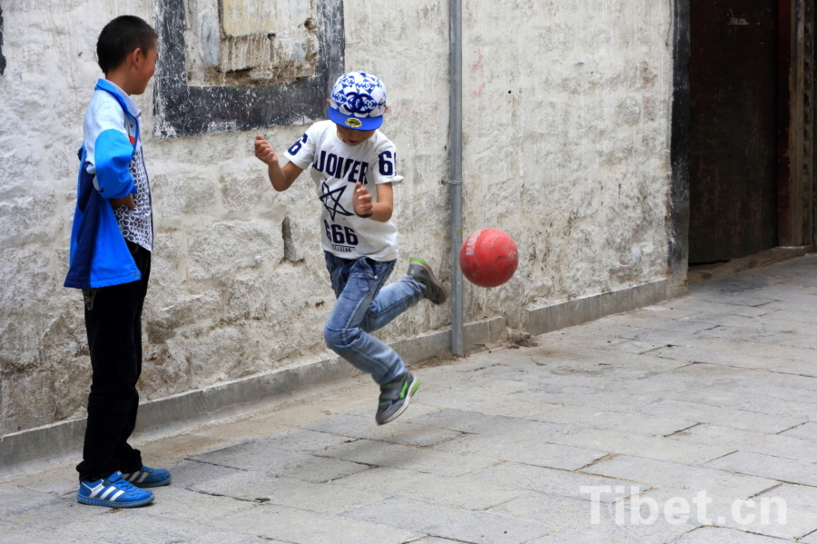 Photo taken on Jun.21, 2015 shows several Tibetan children playing a football game in an alley of the Barkor Street, Lhasa, capital of southwest China’s Tibet Autonomous Region. [Photo/China Tibet Online]