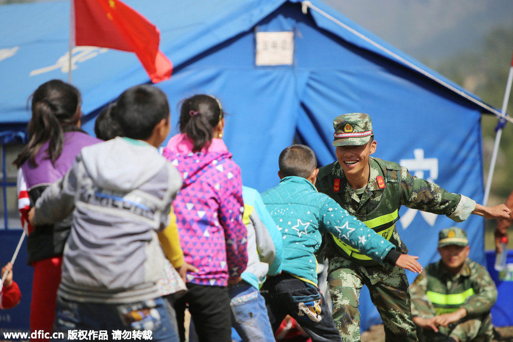 Twenty soldiers of public security frontier forces help relocate a makeshift school in a quake affected region to more open, safer flatlands, in Gyirong county, Shigatse City of Southwest China's Tibet Autonomous Region on Wednesday. The pupils' school was damaged in a 7.5 magnitude earthquake that jolted Gyirong on Tuesday, before they moved to the prefabricated one. The photos shows the soldiers playing a game called "the eagle catches the chickens" with the pupils. [Photo/IC]