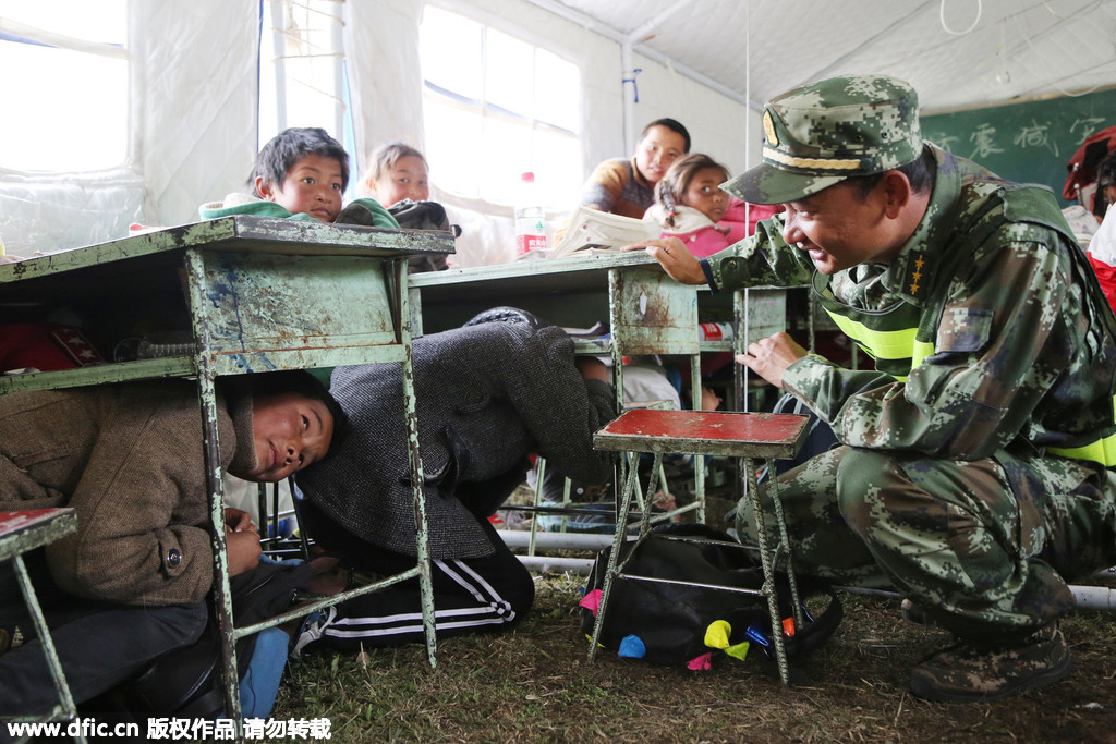 Soldiers of public security frontier forces in Gyirong, Tibet Autonomous Region, who are helping to relocate a makeshift school to more open, safer flatlands, play games with the pupils. [Photo/IC]