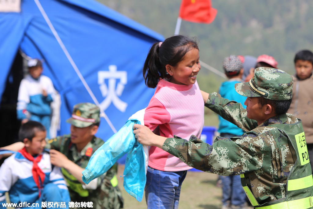 A soldier helps a pupil put her jacket. On Wednesday, twenty soldiers of public security frontier forces helped relocate a makeshift school in a quake affected region to more open, safer flatlands, in Gyirong county, Shigatse City of Southwest China's Tibet Autonomous Region .[Photo/IC]