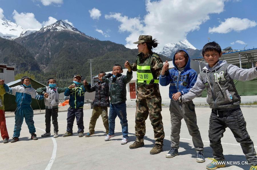 A soldier plays games with pupils at a primary school in quake-hit Gyirong Town, Shigatse City, southwest China's Tibet Autonomous Region, May 4, 2015. Soldiers of Gyirong frontier inspection station held a psychological counseling lesson for junior students on Monday, after the region being hit by the massive Nepal earthquake on April 25. (Xinhua/Liu Dongjun)