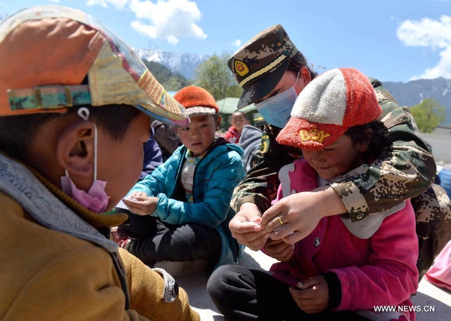 A soldier plays games with pupils at a primary school in quake-hit Gyirong Town, Shigatse City, southwest China's Tibet Autonomous Region, May 4, 2015. Soldiers of Gyirong frontier inspection station held a psychological counseling lesson for junior students on Monday, after the region being hit by the massive Nepal earthquake on April 25. (Xinhua/Liu Dongjun)