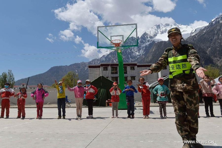 A soldier plays games with pupils at a primary school in quake-hit Gyirong Town, Shigatse City, southwest China's Tibet Autonomous Region, May 4, 2015. Soldiers of Gyirong frontier inspection station held a psychological counseling lesson for junior students on Monday, after the region being hit by the massive Nepal earthquake on April 25. (Xinhua/Liu Dongjun)