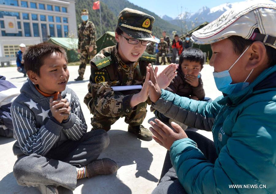 A soldier plays games with pupils at a primary school in quake-hit Gyirong Town, Shigatse City, southwest China's Tibet Autonomous Region, May 4, 2015. Soldiers of Gyirong frontier inspection station held a psychological counseling lesson for junior students on Monday, after the region being hit by the massive Nepal earthquake on April 25. (Xinhua/Liu Dongjun)