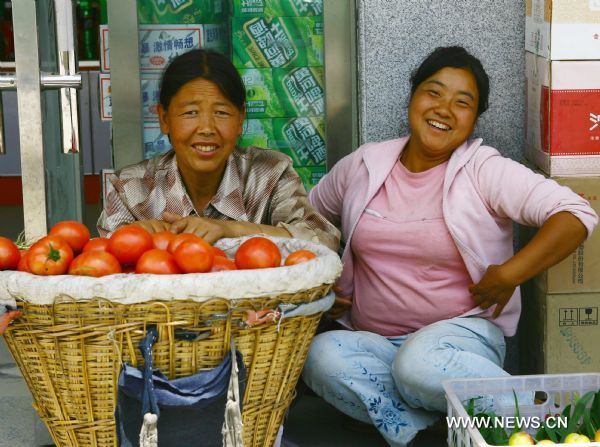 Vendors selling tomatoes and fruits simle at the camera in Zhouqu County of Gannan Tibetan Autonomous Prefecture, northwest China's Gansu Province, Aug. 2, 2011. After a year's recovery from the deadly mudslide which occurred on Aug. 8, 2010, the beautiful county of Zhouqu has resumed hustle and bustle as the life goes on the way it did. [Photo/Xinhua]