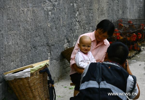 A baby smiles as a photographer shoots her in Zhouqu County of Gannan Tibetan Autonomous Prefecture, northwest China's Gansu Province, Aug. 2, 2011. After a year's recovery from the deadly mudslide which occurred on Aug. 8, 2010, the beautiful county of Zhouqu has resumed hustle and bustle as the life goes on the way it did. [Photo/Xinhua]