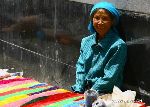  A vendor selling yarn simles at the camera in Zhouqu County of Gannan Tibetan Autonomous Prefecture, northwest China's Gansu Province, Aug. 2, 2011. After a year's recovery from the deadly mudslide which occurred on Aug. 8, 2010, the beautiful county of Zhouqu has resumed hustle and bustle as the life goes on the way it did. [Photo/Xinhua]