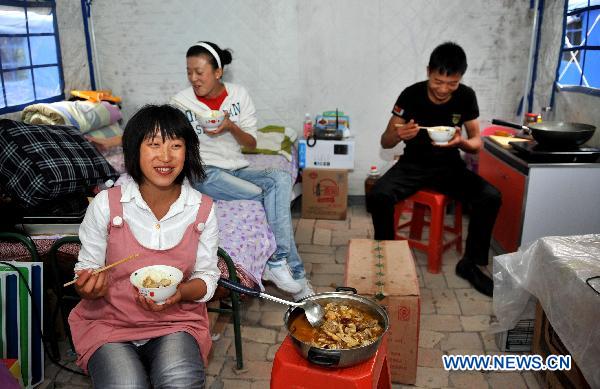 Yan Hongmei (front) has dinner with family members at the temporary shelter in mudslides-hit Zhouqu County, northwest China's Gansu Province, Sept. 22, 2010. Local residents celebrated the first Mid-Autumn Festival after the mudslides at the temporary shelter on Wednesday.