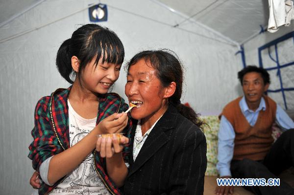 A twelve-year-old girl feeds her mother mooncake at the temporary shelter in mudslides-hit Zhouqu County, northwest China's Gansu Province, Sept. 22, 2010. Local residents celebrated the first Mid-Autumn Festival after the mudslides at the temporary shelter on Wednesday.