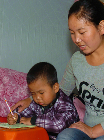 Yang Yahong teaches her nephew how to write in the new Shachuan district of mudslide-battered Zhouqu county.