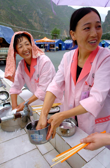 Zhang Gongjian (R), health inspector from Zhouqu health bureau, washes dishes with her colleague, in the mudslide-battered Zhouqu county.