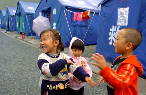 Five-year-old Lei Caiying (R) plays with his friends near their tent homes in mudslide-battered Zhouqu county.