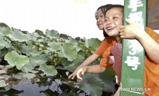 Gao Wenyan(R) and Shang Haijiao view the scenery of lotus flowers at the Summer Palace in Beijing, capital of China, Aug. 30, 2010.