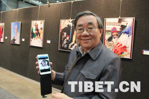 Huang Tingrong takes a photo for his favorite picture with a mobile phone at the "Beauty of Tibet" Painting and Photography Exhibition 2013.[Photo/China Tibet Online]