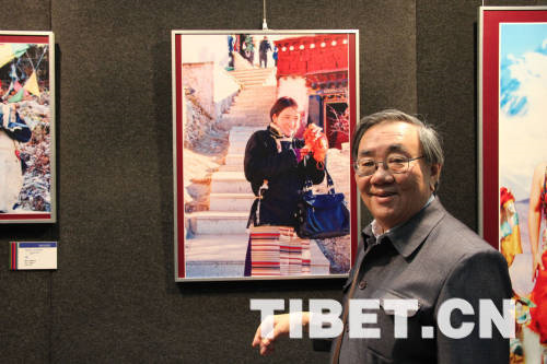 Huang Tingrong takes a photo with one of his favorite pictures at the "Beauty of Tibet" Painting and Photography Exhibition 2013.[Photo/China Tibet Online]