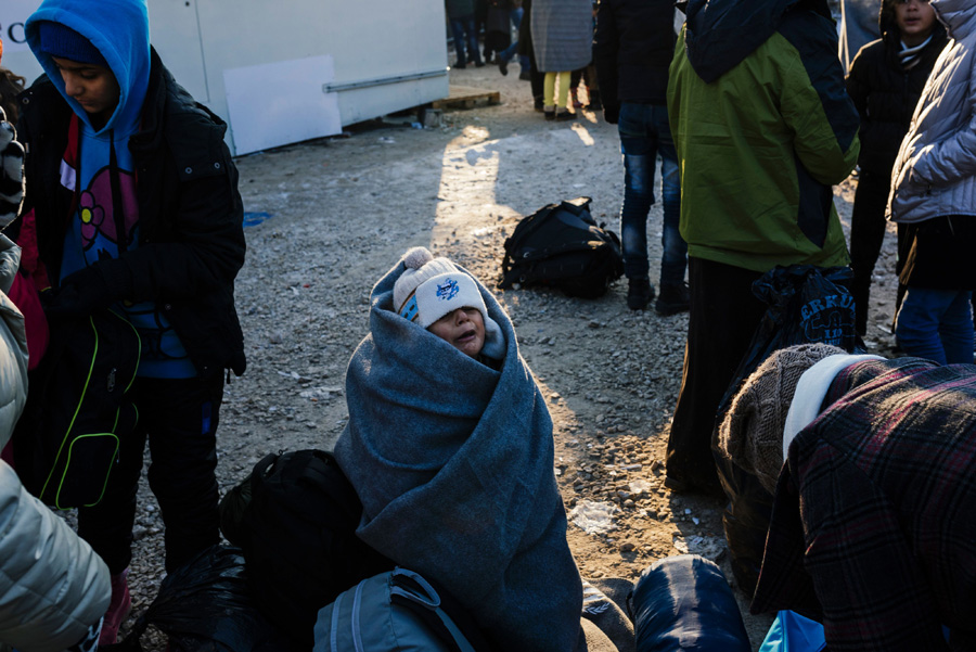 A child, wrapped in a blanket, cries from the cold, as migrants and refugees wait for a bus at a registration camp in southern Serbian town of Presevo on January 20, 2016, as temperature fall to minus 15 Celsius degrees. As refugees continued to flow from Greece through the Balkans on their way to western Europe, aid workers sounded alarms over inadequate shelter from the current freezing temperatures and snowy conditions, particularly for children. [Photo/AFP]