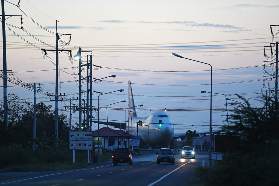 This picture taken on January 19, 2016 shows traffic along a rural road going past a decommissioned Boeing 747 passenger aircraft sitting on a field in Nakhon Pathom province west of Bangkok.[Photo/CFP]