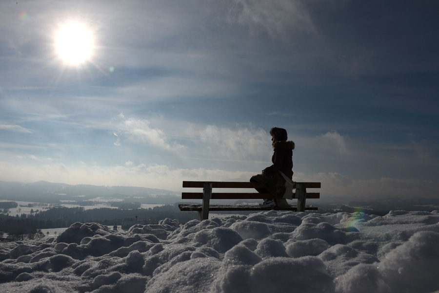 A young girl sits on a bench and enjoys the sunny winter weather with temperatures by the freezing point at a snowy landscape near the small Bavarian village Irschenberg, southern Germany, on January 20, 2016. [Photo/AFP] 